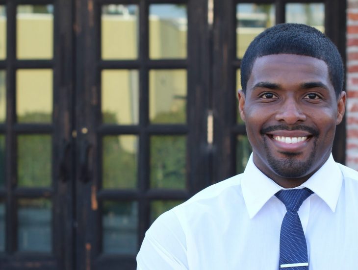 Smiling African student or teacher at the entrance of the school crossing his arms