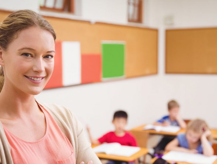 Teacher smiling at camera at top of classroom