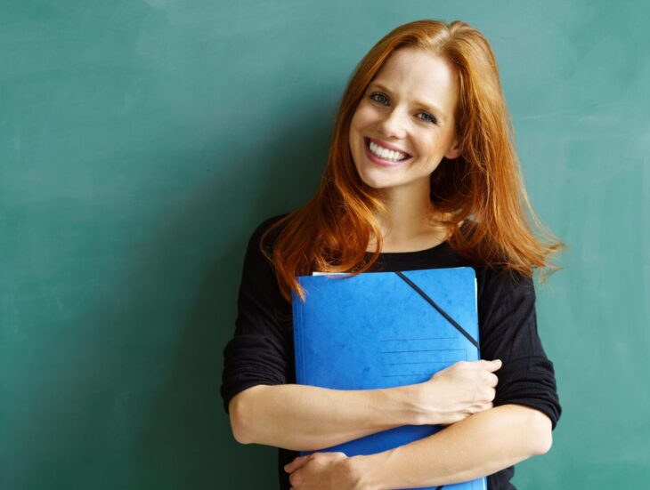 Woman holding folder in front of chalkboard