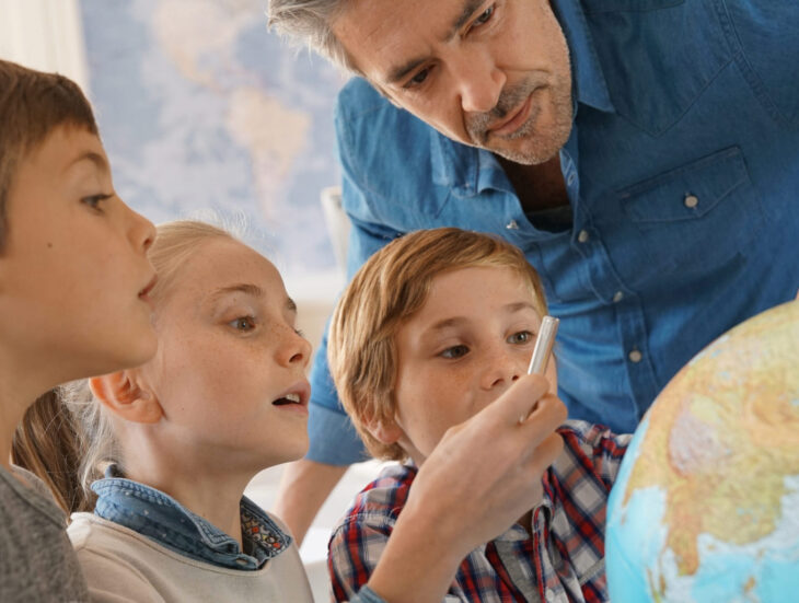 Teacher with kids in social studies class looking at globe