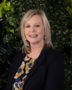 Headshot of Jenny Barnett, smiling against some foilage